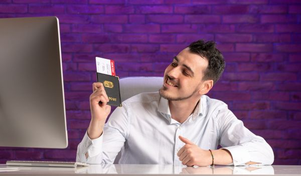 front-view-office-worker-sitting-his-working-place-holding-tickets-passport