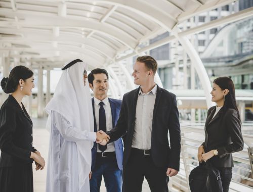 Portrait of business partners greeting one another by handshaking on the way to office.
