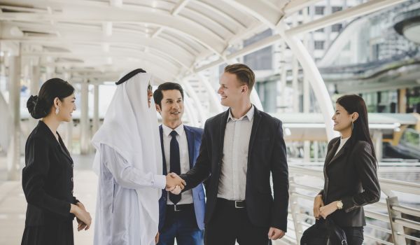 Portrait of business partners greeting one another by handshaking on the way to office.