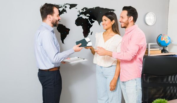 you-are-all-set-your-vacations-sales-representative-giving-passports-plane-tickets-young-woman-man-their-holiday-trip-travel-agency_662251-2215